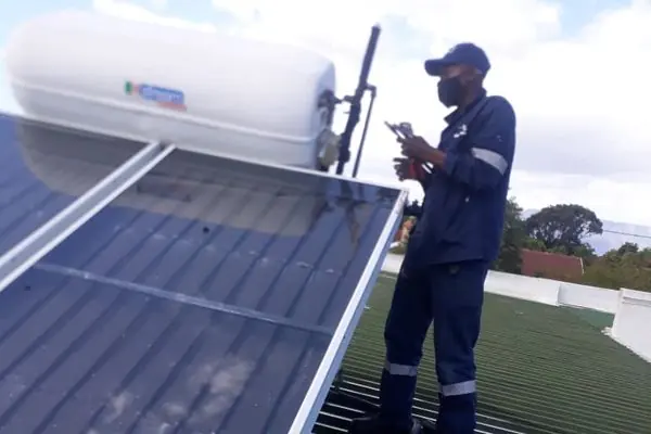 Plumber checking a roof-mounted solar geyser and panel