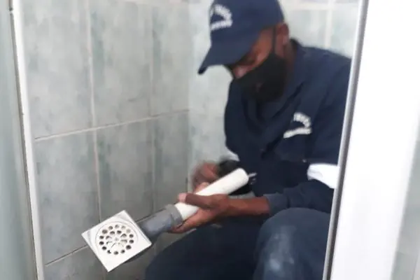 Plumber fitting a new floor drain in a tiled shower