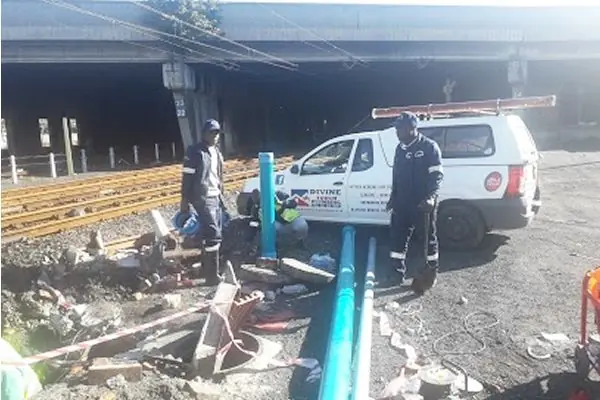 Divine Touch team laying new water pipe in a trench beside their vehicle